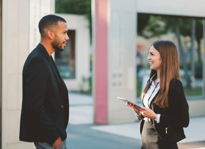 Two business professionals, a man and a woman, standing and having a friendly conversation